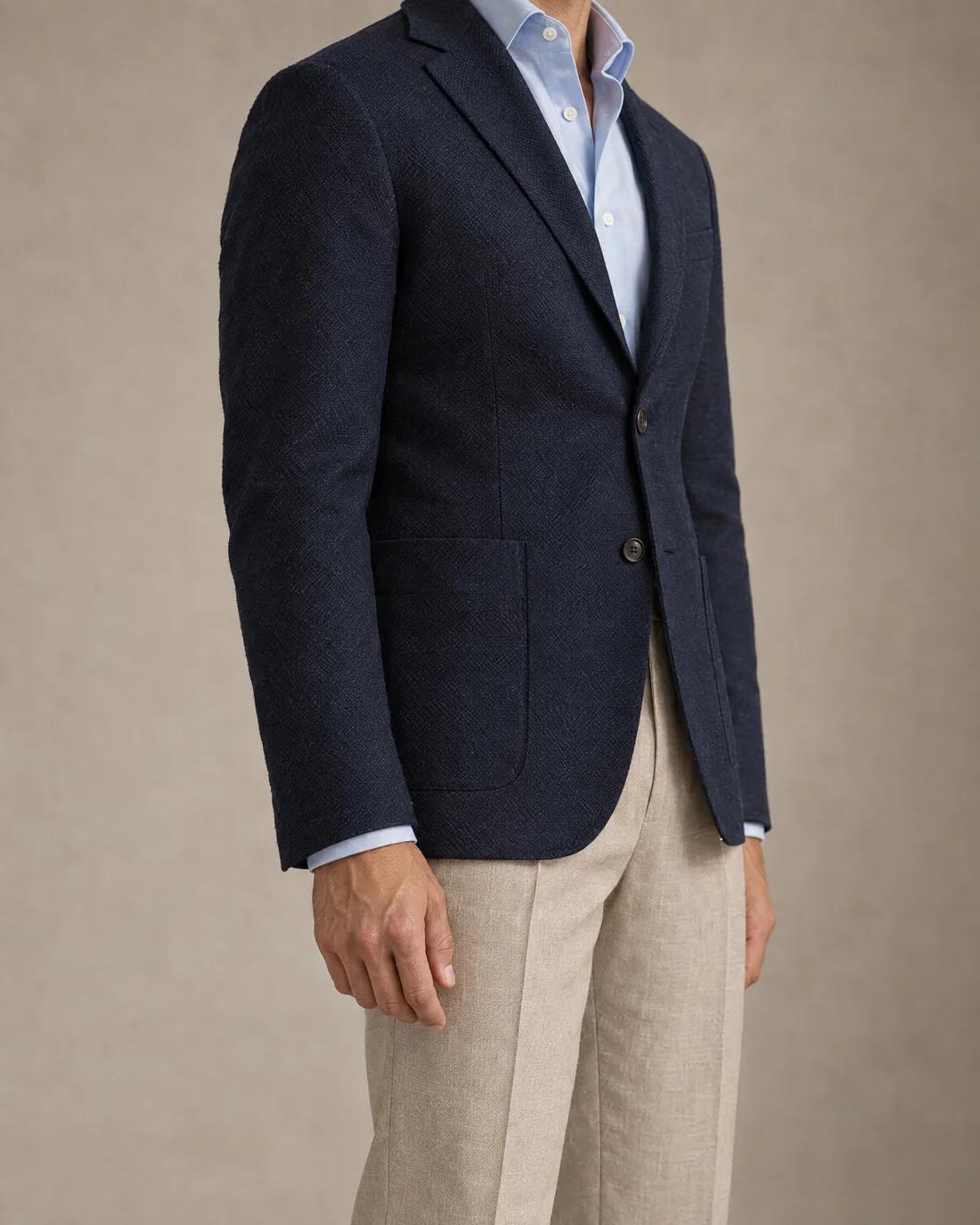 The navy jacket from the side, its hem level with the curled thumb.